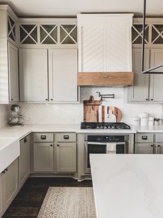 a kitchen with gray cabinets and white counter tops