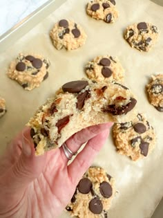 someone holding up a cookie with chocolate chips on it