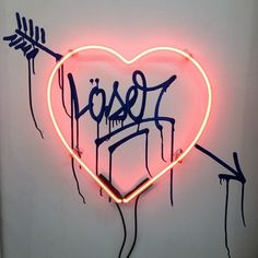 a heart shaped neon sign with the word love painted on it and arrows sticking out of it