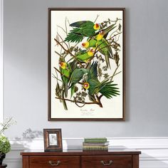 a group of green birds sitting on top of a wooden dresser next to a window