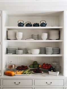 a kitchen with white cupboards filled with plates and bowls