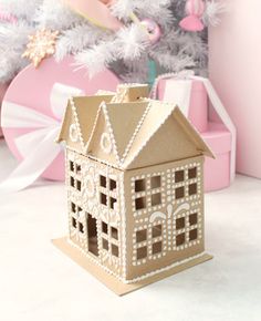 a paper house sitting next to a christmas tree