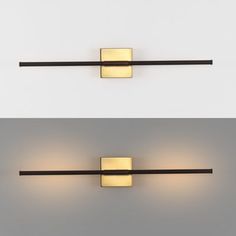 two wall lights that are next to each other on a white wall, one is gold and the other is black