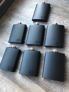 six black flasks sitting on top of a wooden table