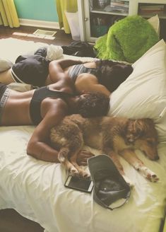 a woman laying on top of a bed next to a dog