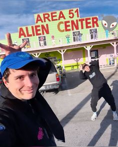 two men standing in front of a building with a sign on it that says area 51 alien center