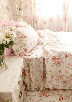 a white bed sitting next to a window covered in pink and white flowers on top of it