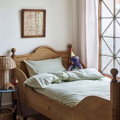 a bed in a bedroom with a teddy bear on it's head and green checkered sheets