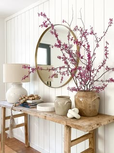 a table with vases and a mirror on top of it next to a lamp