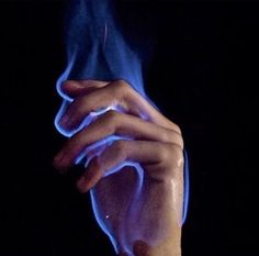 a person's hand holding something with blue light coming out of the top of it