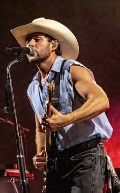 a man wearing a cowboy hat singing into a microphone