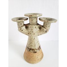 a ceramic candle holder with three candles on it's top and one in the middle