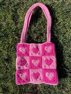 a pink crocheted bag laying on the grass