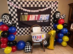 a birthday party with balloons and decorations in the shape of checkered squares, cars, and soccer balls