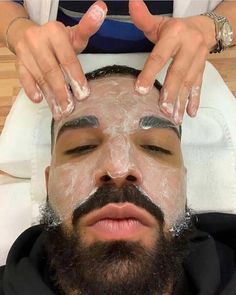 a man is shaving his face with soap on his forehead and hands over his head