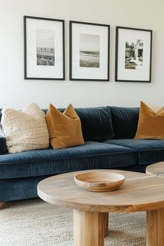 a living room with blue couches and pictures on the wall above them, along with a wooden coffee table