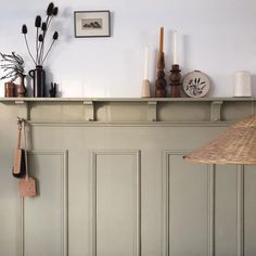 a shelf with various items on it in front of a wall mounted clock and lamp