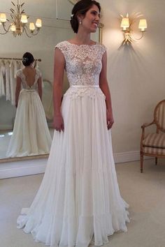 a woman standing in front of a mirror wearing a wedding dress