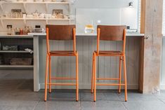 two wooden chairs sitting next to each other in a kitchen