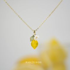 a close up of a necklace with a lemon and flower charm on it's chain