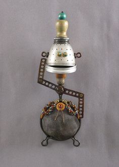 a small bell on top of a metal object with beaded accents and beads around it