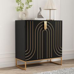 a black cabinet with gold lines on the front and bottom, next to a lamp