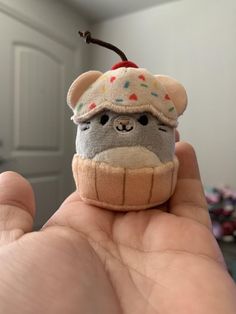 a hand holding a small stuffed animal in a cupcake shape with sprinkles