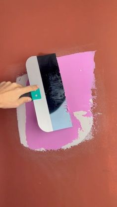 someone is painting the wall with pink and white paint