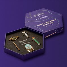 the harry potter pin set is in a purple box with gold trimmings on it