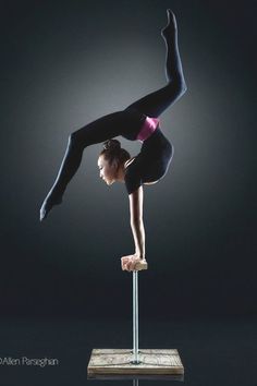 a woman is doing an acrobatic trick on a pole