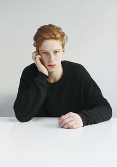 a woman sitting at a white table with her hand on her head and looking off to the side