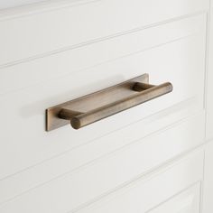 a close up of a door handle on a white cabinet