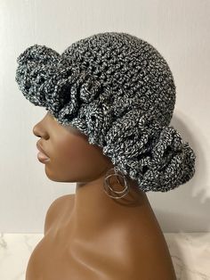 a mannequin head wearing a black and white crochet hat with silver hoop earrings