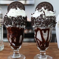 two glasses filled with ice cream and oreo cookies sitting on top of a table