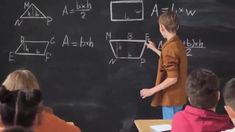 a young boy standing in front of a blackboard