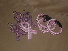 three pieces of pink and white crocheted ribbon are on a brown sheet with black straps