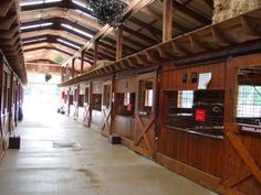 the inside of a building with wooden walls and windows on each side, along with hay bales hanging from the ceiling