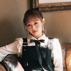 a woman sitting on top of a couch wearing a black and white dress with bow ties