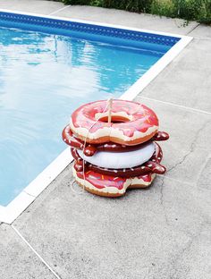 an inflatable donut float sitting next to a swimming pool with a hot dog on it