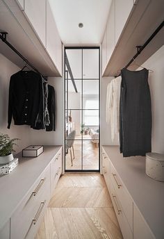 an empty walk in closet with clothes hanging on the wall and doors open to let in light