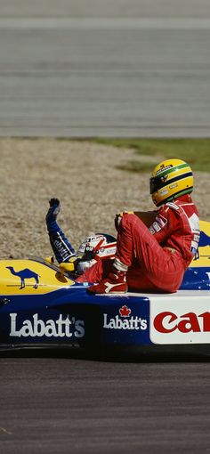 a man riding on the back of a blue and yellow race car