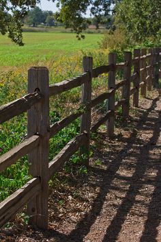 a wooden fence in front of a grassy field