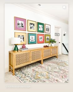 a living room with pictures on the wall and a rug in front of an entryway