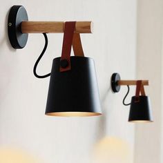 three lamps are hanging on the wall next to each other, one black and one brown