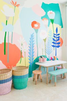 a child's playroom with colorful flowers painted on the wall and toys in baskets