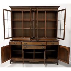 an old wooden bookcase with two doors and three drawers on one side, in front of a white wall