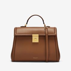 A larger iteration of The Paris, The Midi  Paris is a cosmopolitan top handle bag that showcases our unwavering commitment to craftsmanship. Each one is ethically handmade from sustainable Italian leather and is exquisitely framed with a bombée trim. It features a new trunk inspired gold-plated lock, as well as a detachable and adjustable leather strap for further styling options. The soft cotton-lined interior is capacious enough for all daily essentials. The  Midi   Paris is inspired by the timeless elegance of the City of Light. Leather Top Handle Bag, Quiet Luxury Handbags, Aw24 Outfits, Winter Handbag, Work Tote Bag, Card Holder Purse, Best Wallet, Luxury Packaging, Work Bags