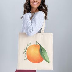 This cotton canvas shoulder tote bag featuring the phrase "La Dolce Vita" with a vibrant orange graphic is perfect for bringing a touch of Italy to your day. Ideal for weekend brunch, farmers market trips, or as a charming Italy-themed gift, this tote is as practical as it is stylish! Prefer this design on a T-Shirt? Visit this link: https://bohemianbloomdesigns.etsy.com/listing/1791107431/la-dolce-vita-shirt-buon-giorno-orange Prefer this design on a Sweatshirt? Visit this link: https://bohemianbloomdesigns.etsy.com/listing/1791109687/la-dolce-vita-buon-giorno-italy Prefer this design on a Baby Tee? Visit this link: https://bohemianbloomdesigns.etsy.com/listing/1791111229/la-dolce-vita-shirt-buon-giorno-preppy 🔑 Key Features: 100% Cotton Canvas: Strong and durable fabric made from spun f Large Capacity Orange Canvas Tote Bag, Orange Canvas Bag For Daily Use, Orange Canvas Travel Bag, Large Capacity Orange Shoulder Canvas Bag, Orange Canvas Bags For Daily Use, Orange Canvas Tote Shoulder Bag, Orange Canvas Shoulder Bag For Everyday Use, Orange Everyday Canvas Shoulder Bag, Eco-friendly Orange Canvas Bag For Everyday Use