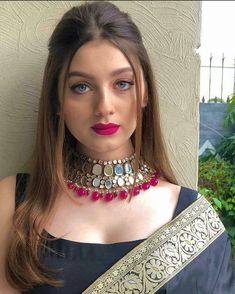 a woman in a black dress wearing a gold and red choker with jewels on it