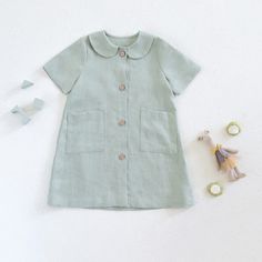 a baby's dress and toy on a white surface